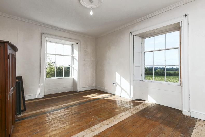 Empty sunlit room with bare floorboards